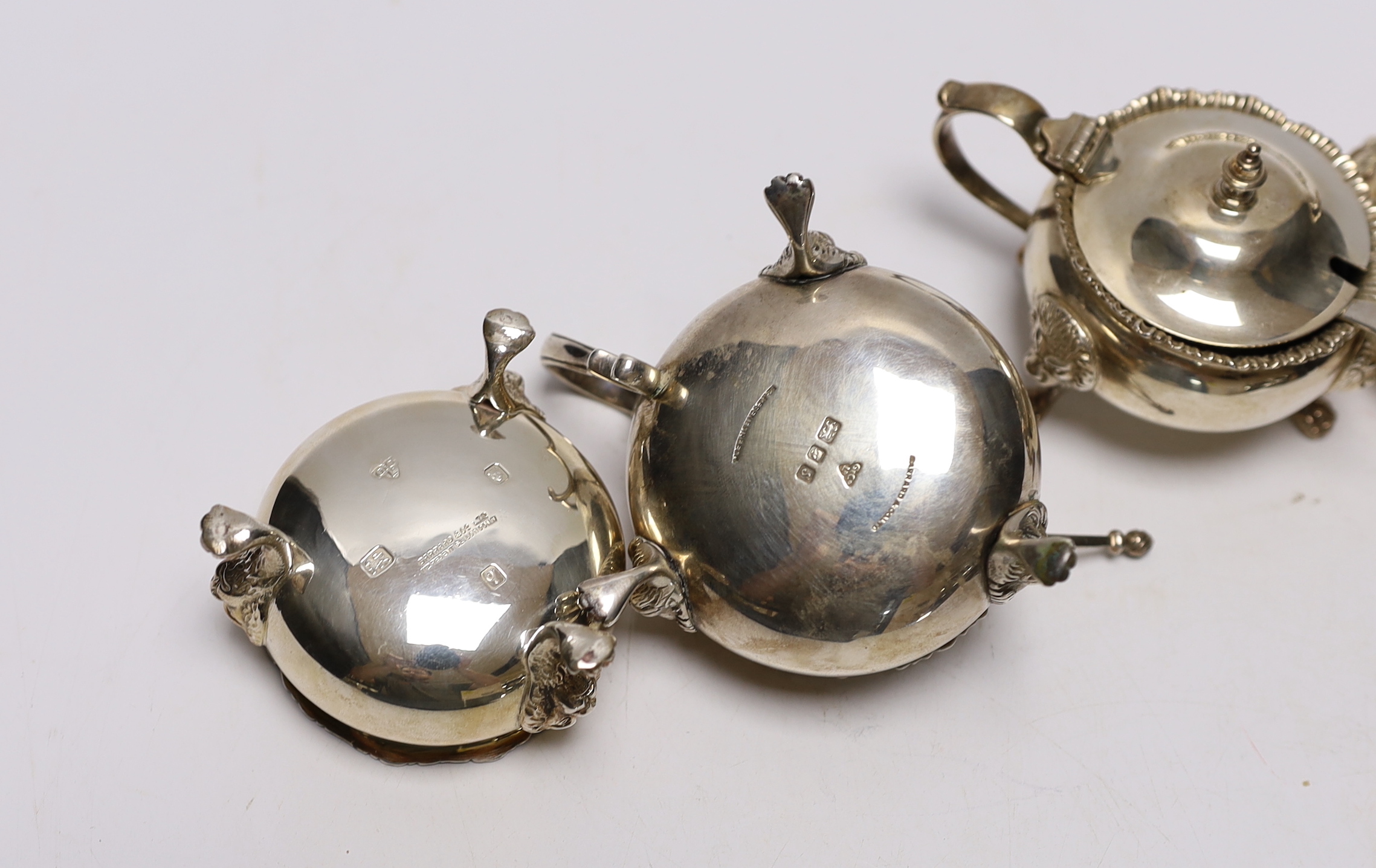 An Elizabeth II silver four piece condiment set by Garrard & Co, London, 1971/73, with blue glass liners and two associated spoons.